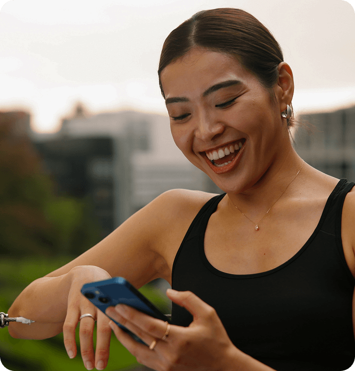 Someone in workout clothes smiling at a message on their phone