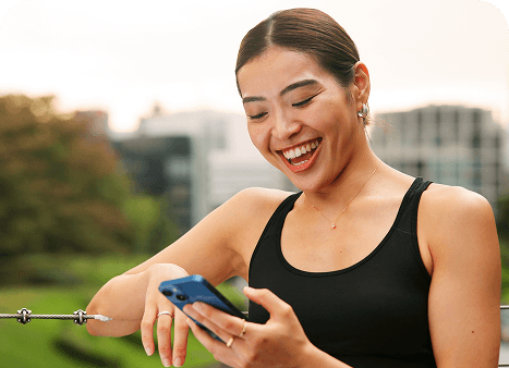 Someone smiling at their phone outdoors in workout clothes